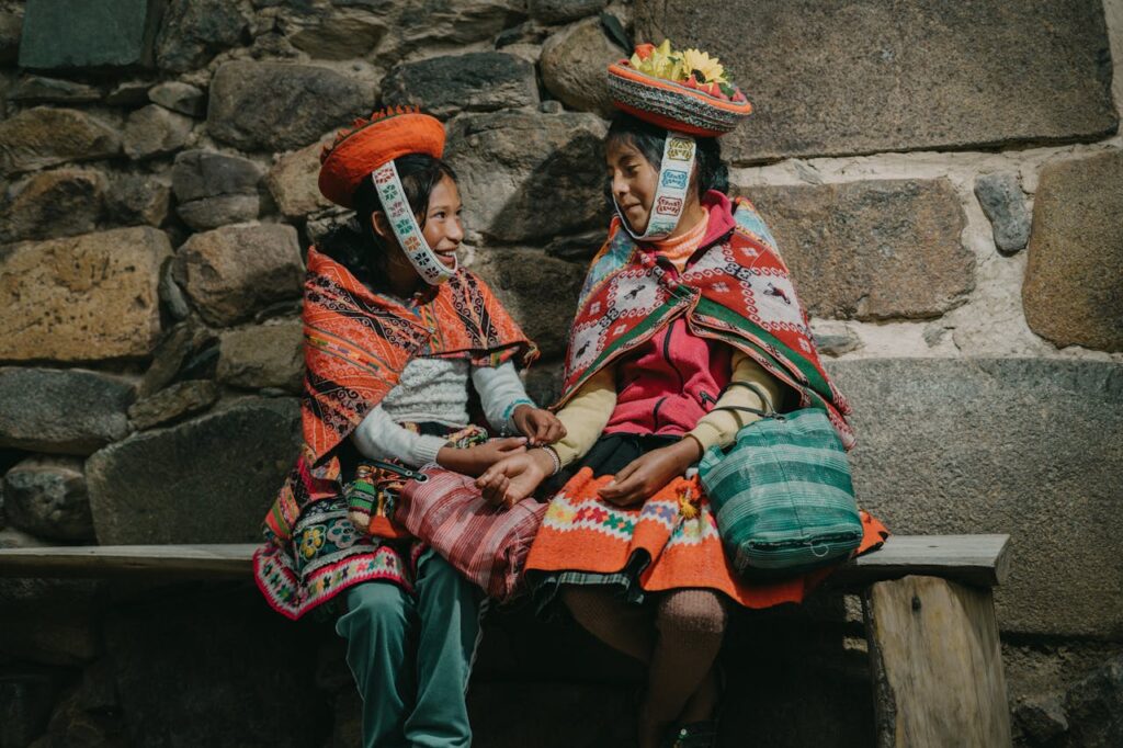 Peruvian Girls Wearing Traditional Clothing, Sitting by a Wall